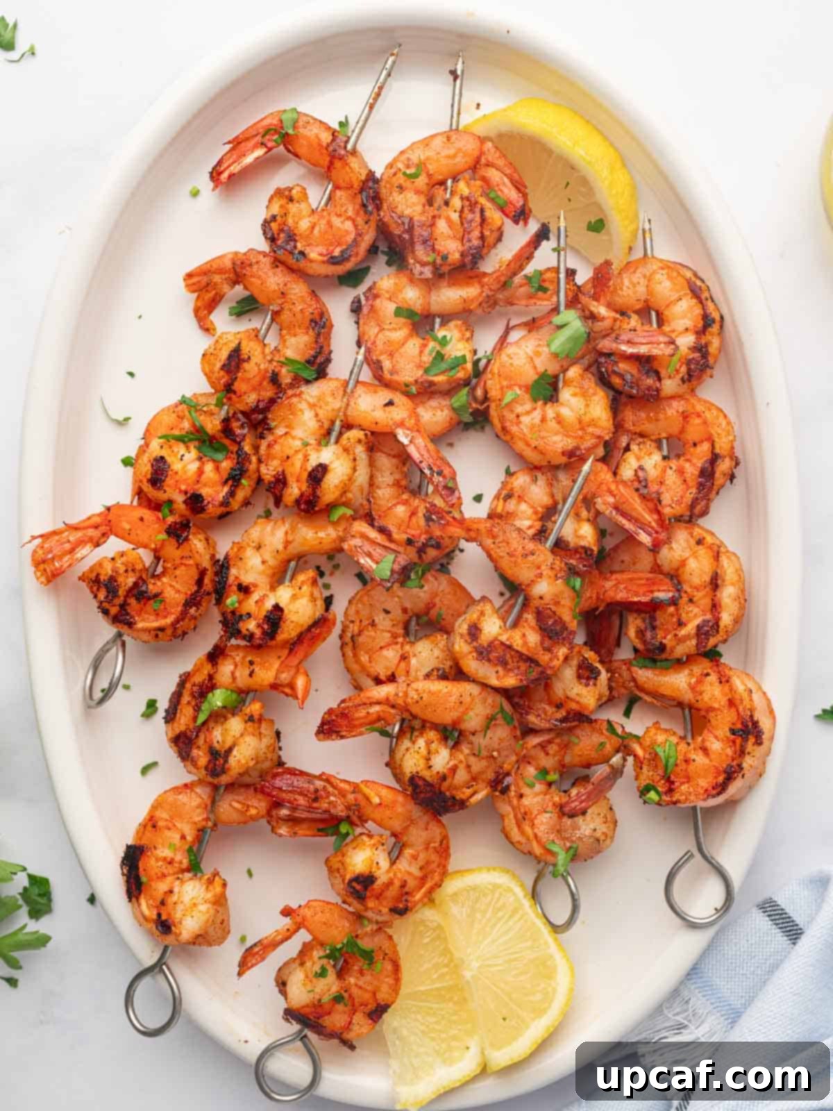 Fiery Cajun Grilled Shrimp 2 A platter with lemon wedges and grilled cajun shrimp skewers.