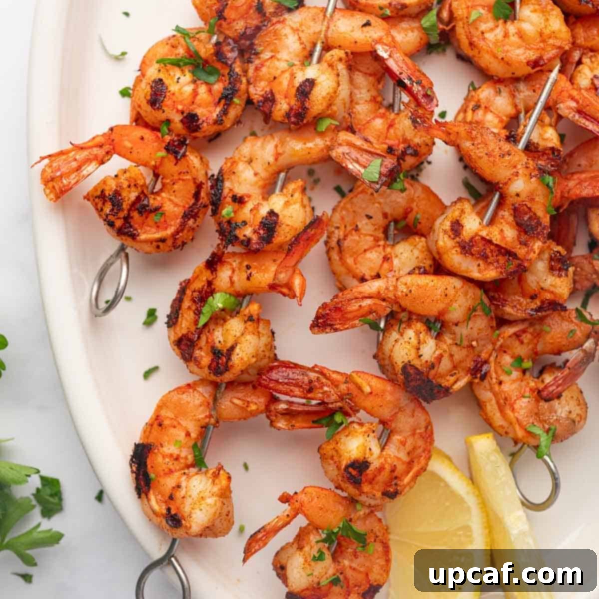 Fiery Cajun Grilled Shrimp 7 Grilled cajun shrimp skewers in a platter with lemon wedges.