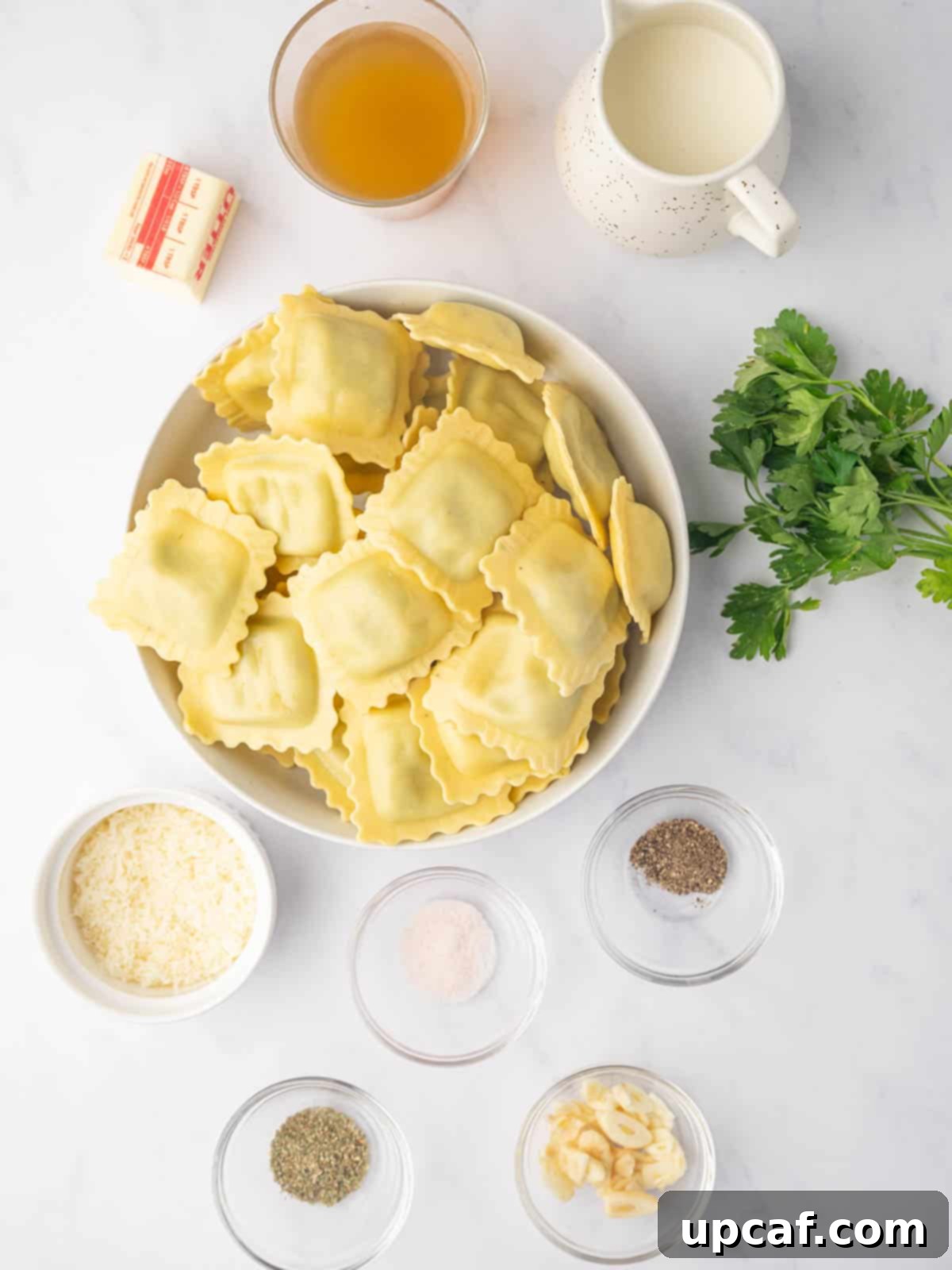 Ingredients needed for spinach and ricotta ravioli, including fresh parsley, butter, garlic, cream, and broth.