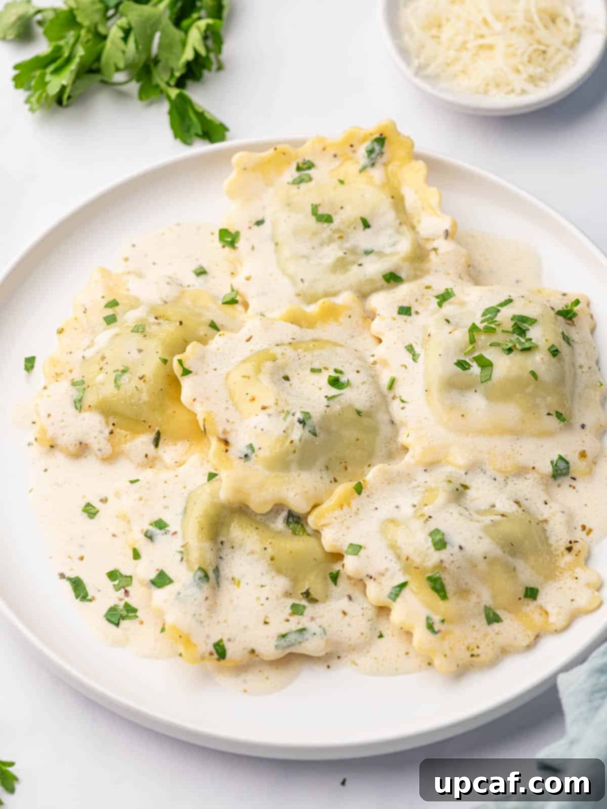 Close up of spinach and ricotta ravioli in a creamy sauce, garnished with parsley.