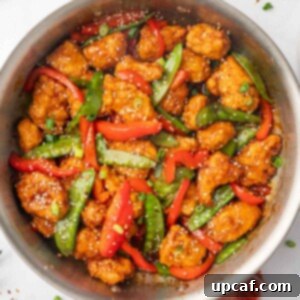 A skillet with sesame seed garnished crispy honey chili chicken and vegetables.