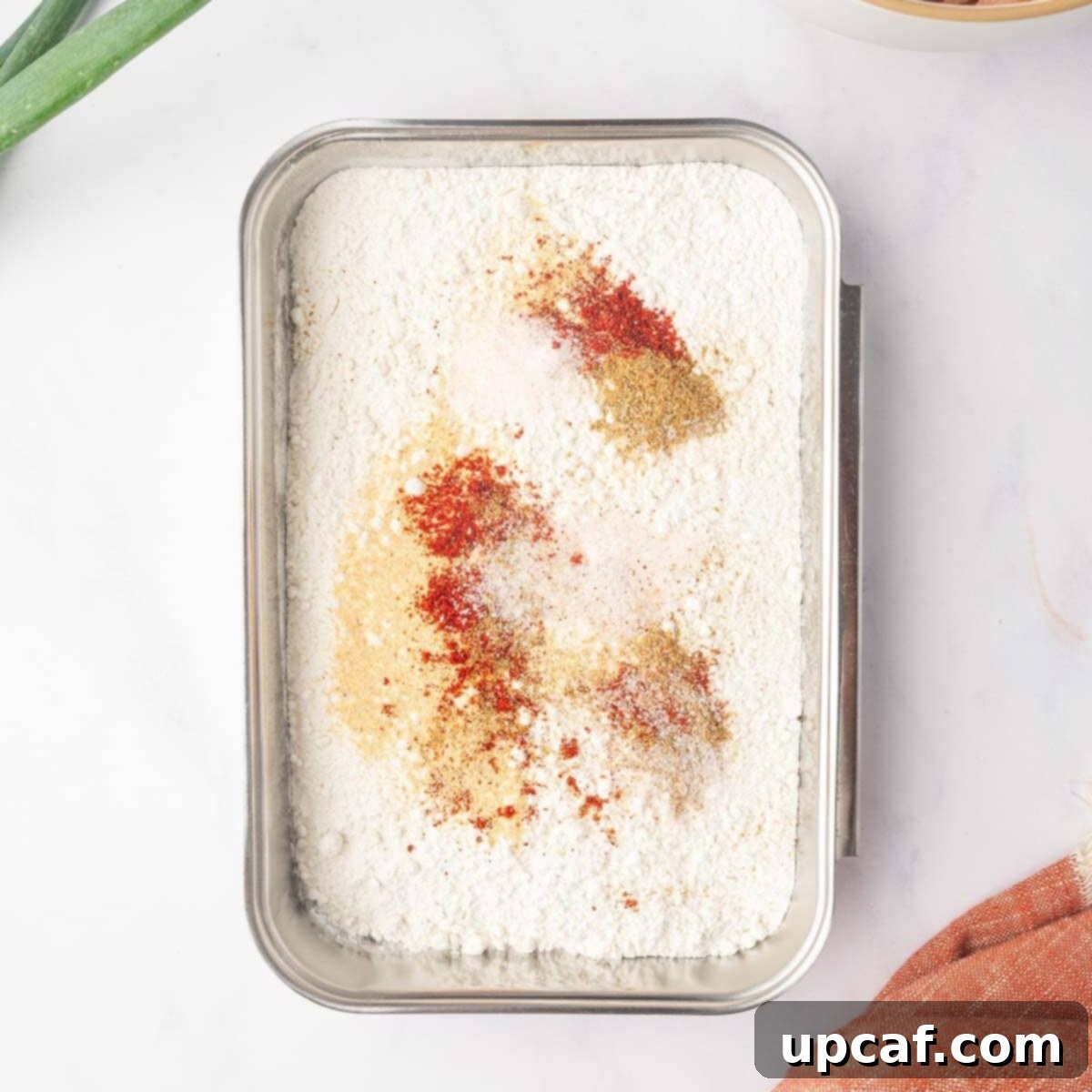 Preparing the flour mixture for dredging the chicken pieces on a cutting board.