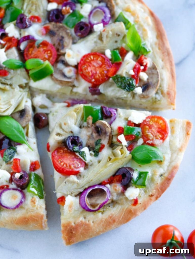 Mediterranean Veggie Pizza Close up of a Mediterranean Veggie Pizza slice being pulled from the pan