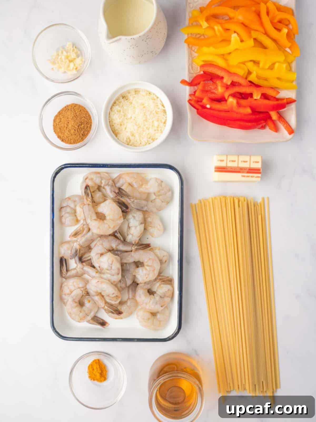 One Love Shrimp Pasta 3 A flat lay of fresh ingredients for Jamaican Shrimp Rasta Pasta, including raw shrimp, colorful bell peppers, dry pasta, and various spices.