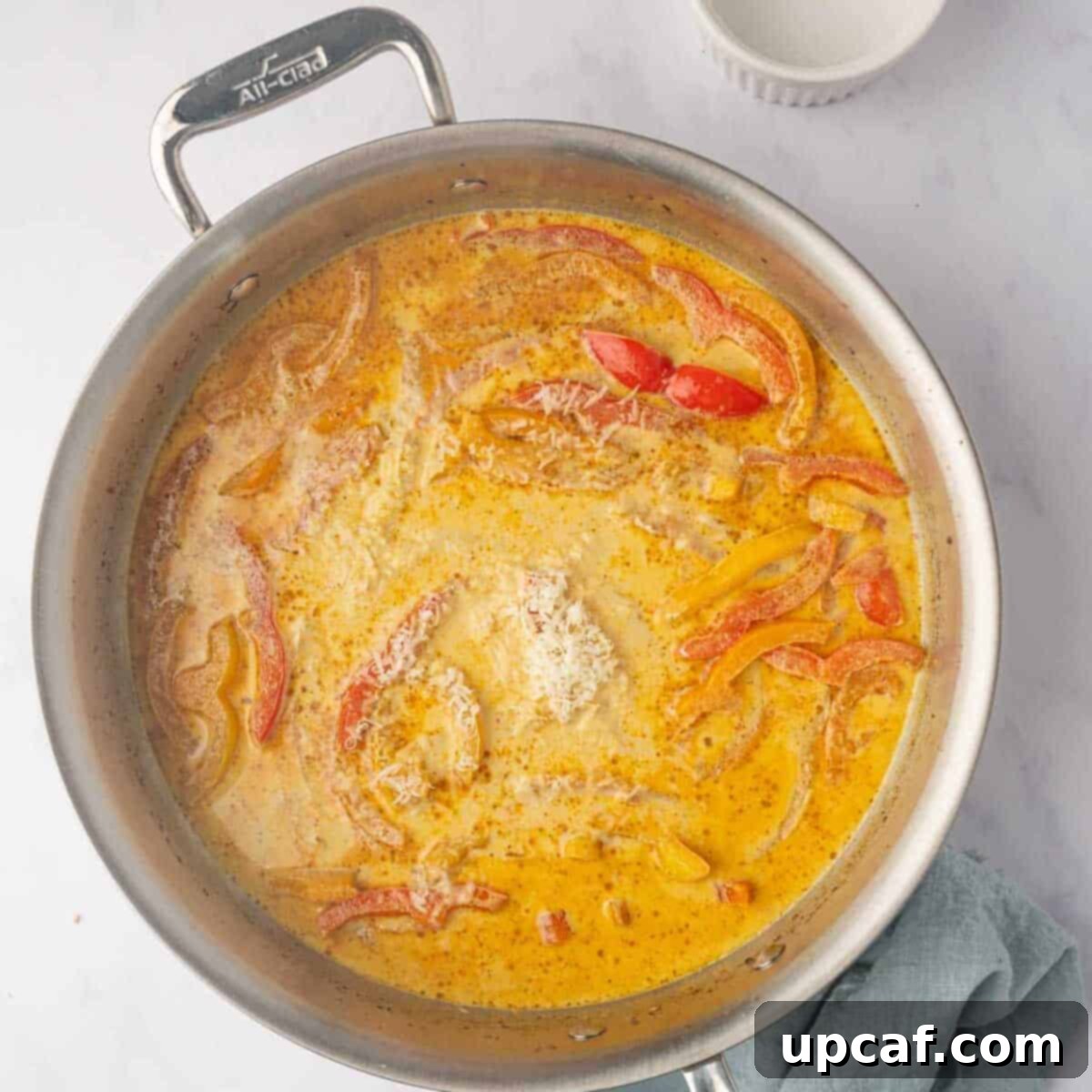 One Love Shrimp Pasta 8 Chicken stock and heavy cream are poured into the skillet, creating a rich, spicy sauce simmering gently.