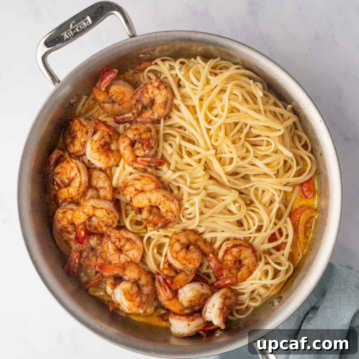 One Love Shrimp Pasta 9 Cooked linguine pasta and shrimp are added back into the skillet with the creamy rasta sauce, being tossed together.