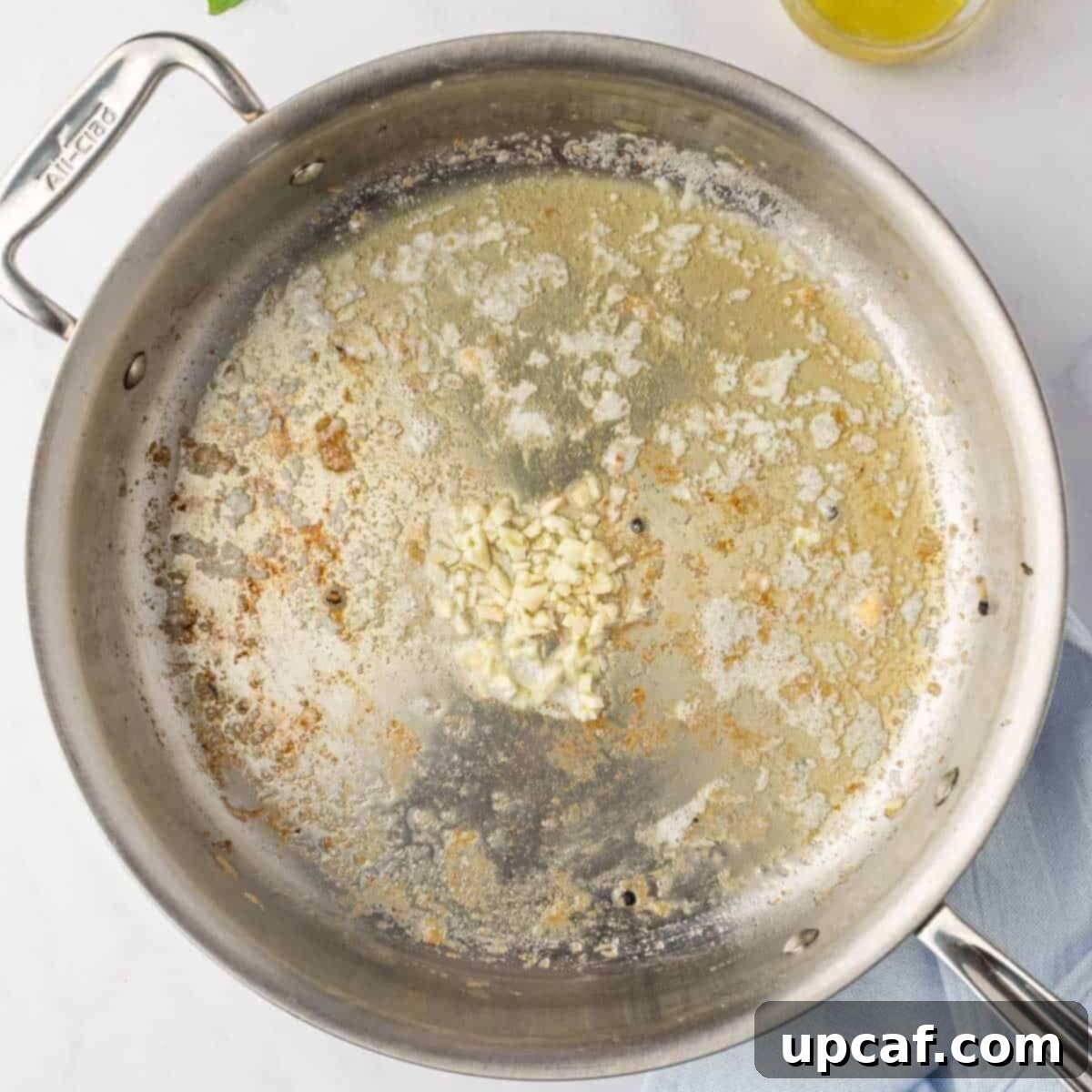 Minced garlic being sautéed in melted butter in a skillet.