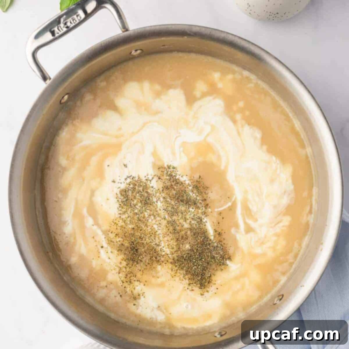 Preparing the creamy sauce with chicken broth and heavy cream in a skillet.