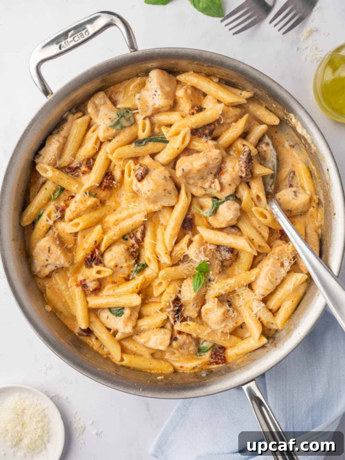 A serving spoon lifting a portion of Marry Me Chicken Pasta from a skillet.