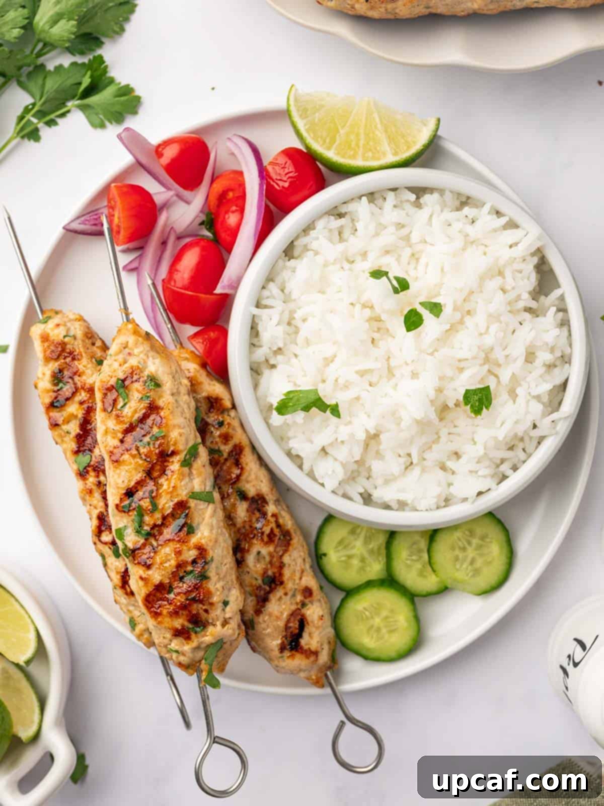 Perfectly Spiced Chicken Kofta 9 A generous serving of grilled chicken kofta presented with fluffy rice and a colorful array of fresh vegetables.