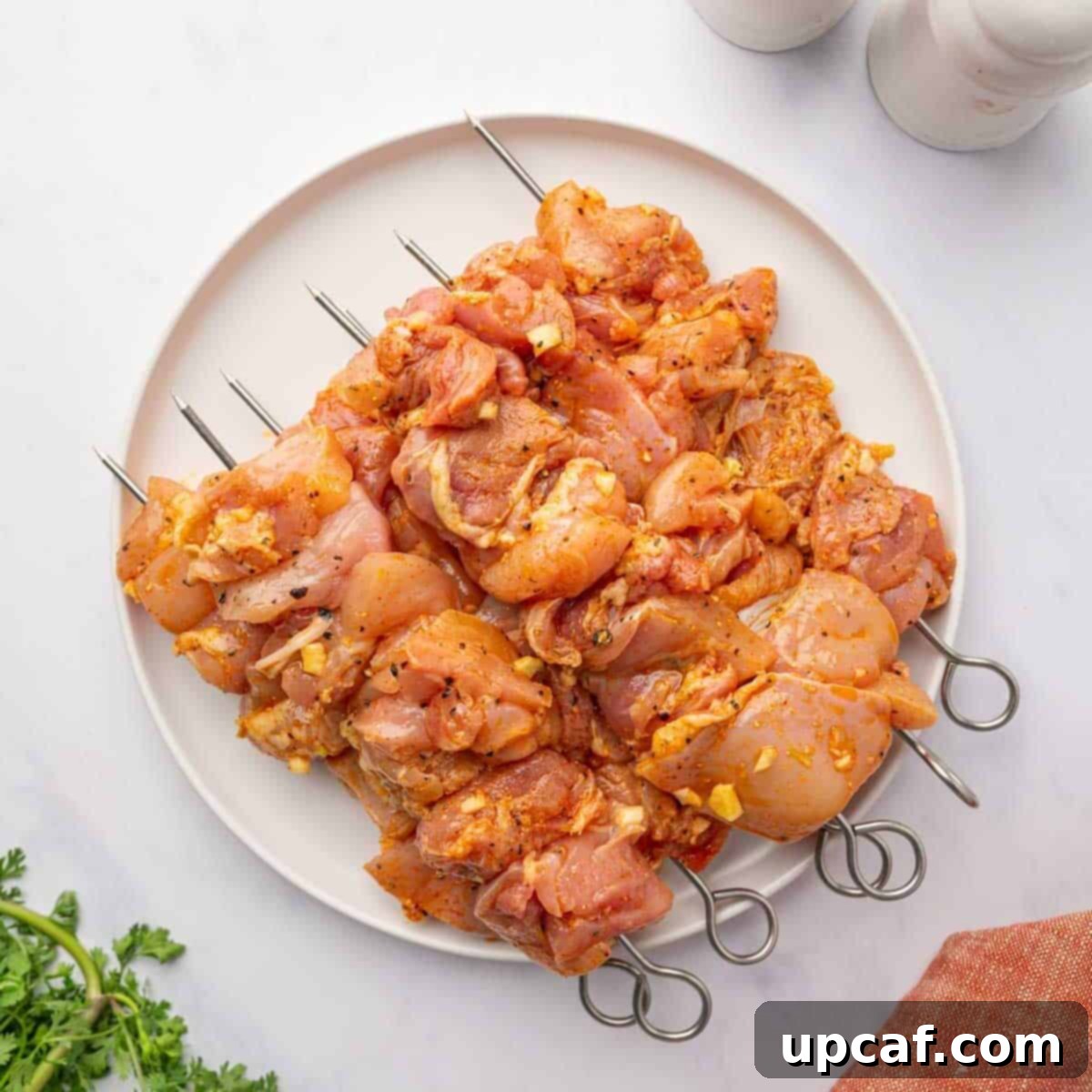 Raw chicken pieces are meticulously threaded onto wooden skewers, ready for grilling.
