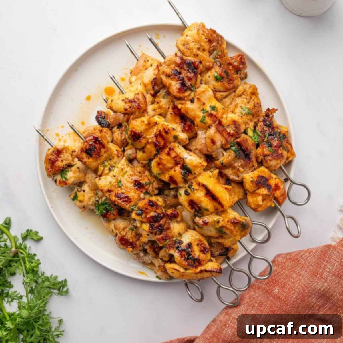 Grilled chicken kabobs arranged artfully on a serving platter, garnished with fresh herbs.