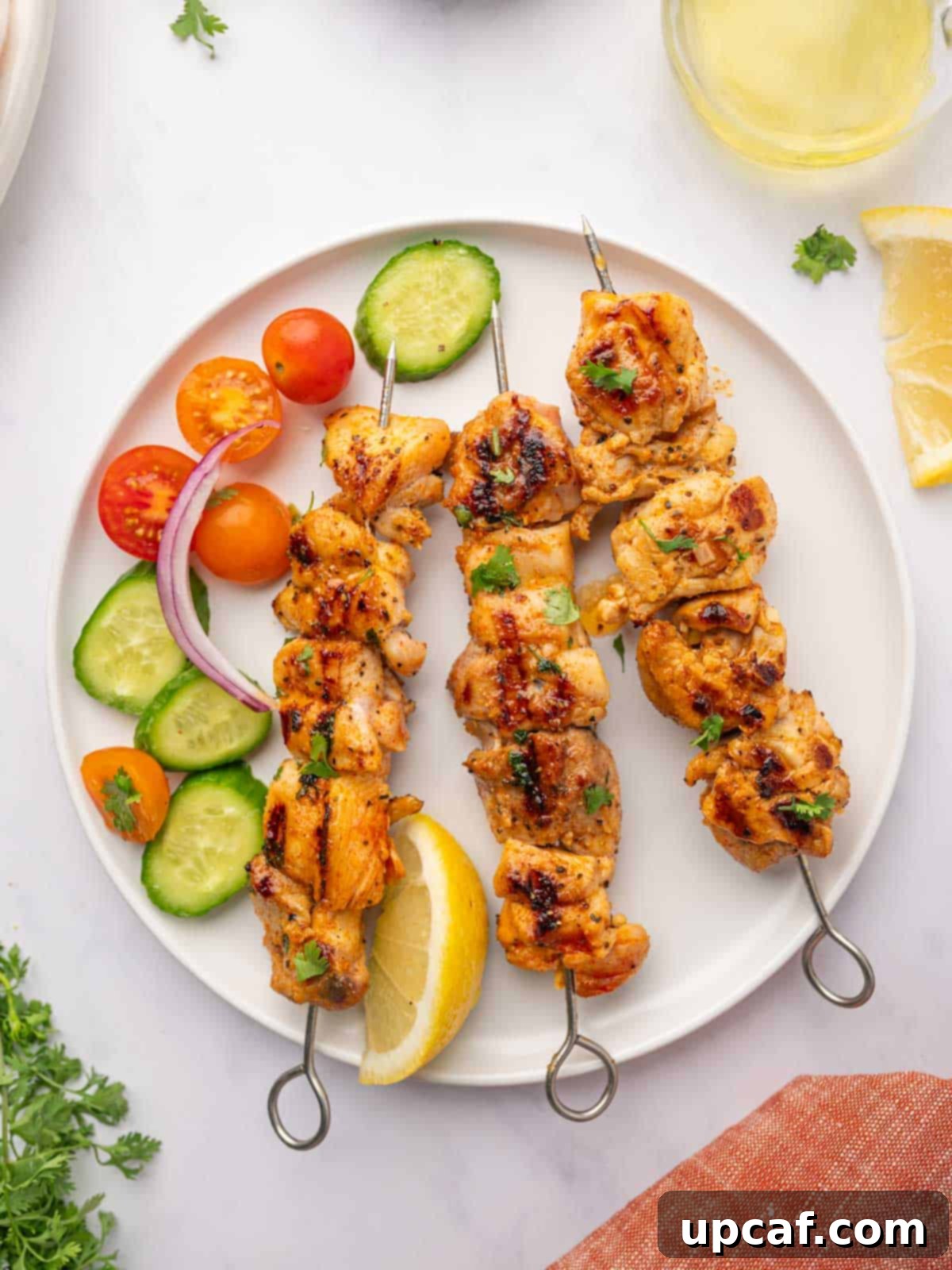 Grilled lemon pepper chicken skewers artfully arranged on a white plate, ready to be served.