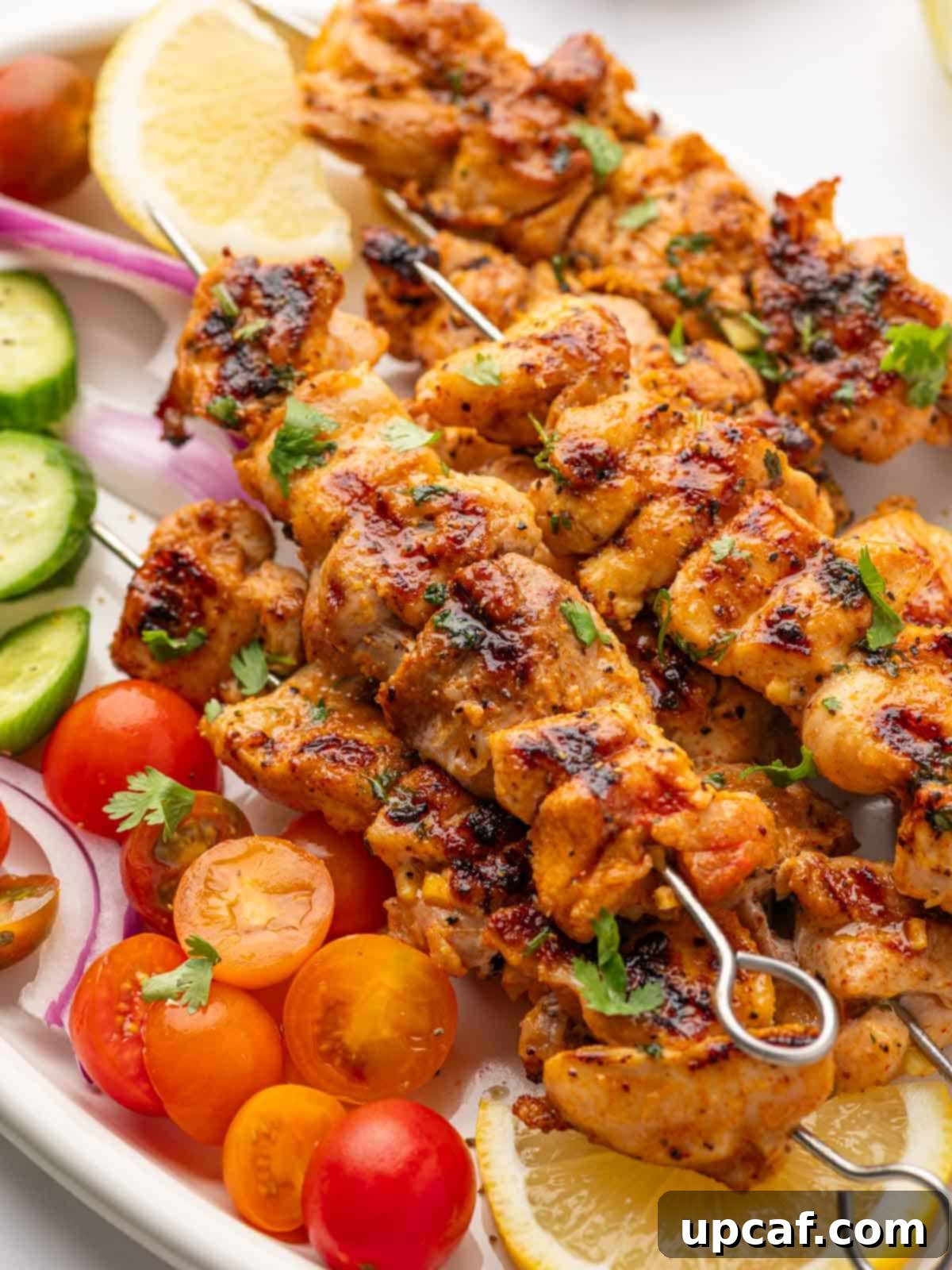 Close up of perfectly grilled lemon pepper chicken thighs on a platter, garnished with fresh herbs.