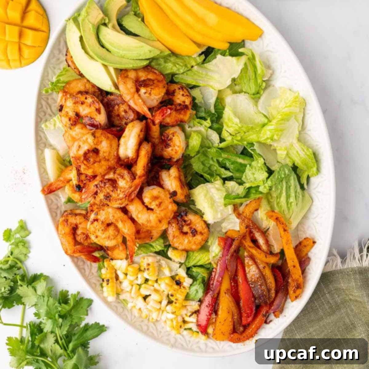 Ingredients for shrimp salad, including grilled vegetables and shrimp, arranged on a platter.