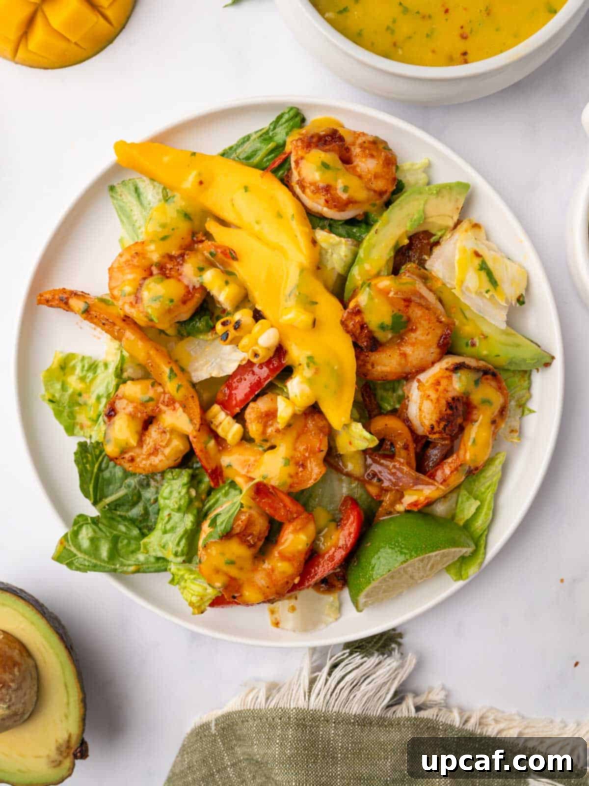 A plate of mango shrimp salad, beautifully presented with vibrant colors of shrimp, mango, and vegetables.
