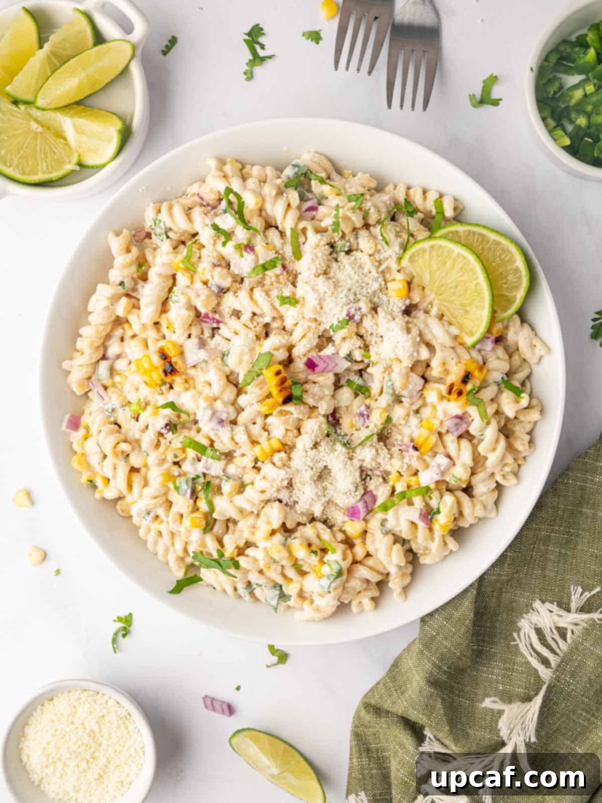 Street corn pasta salad with lime wedges in a bowl.
