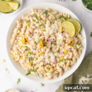 Street corn pasta salad with lime wedges in a bowl.