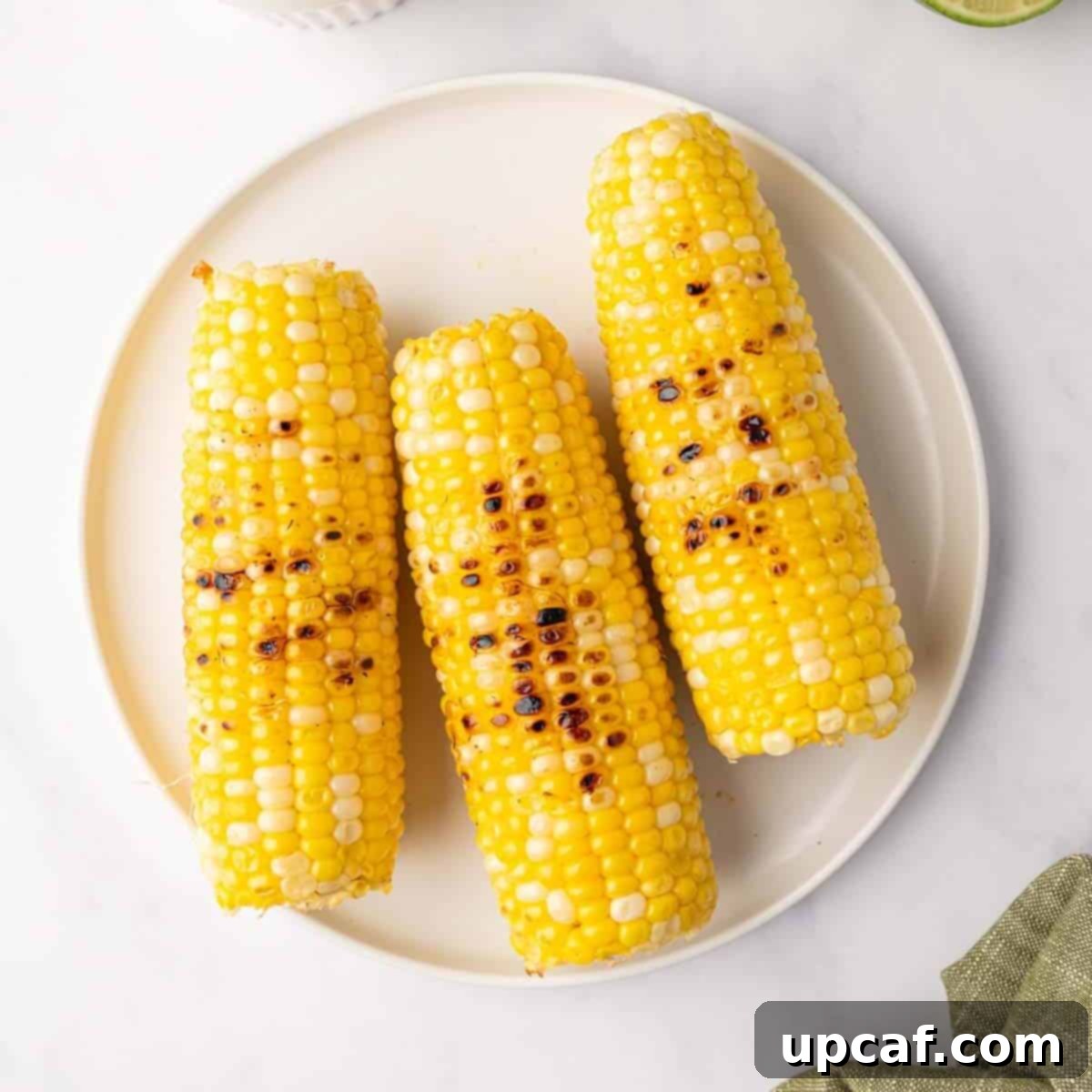 Three ears of grilled corn on a plate.