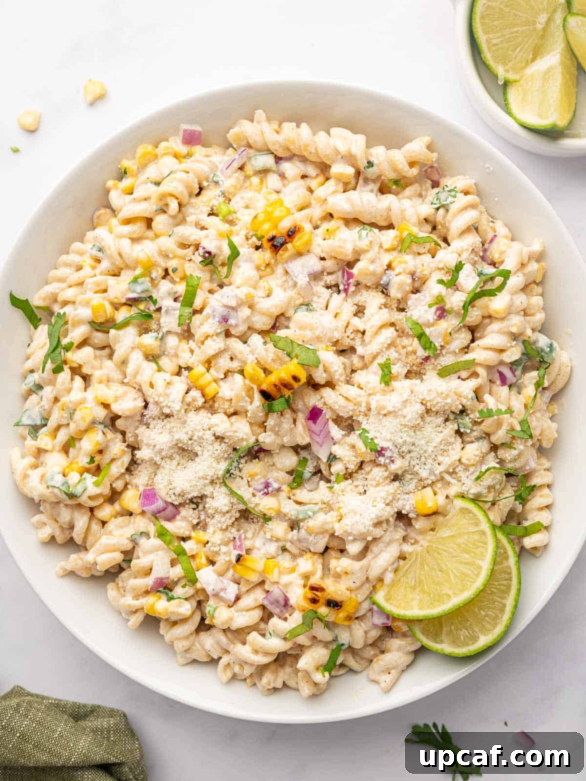 Street corn pasta salad topped with cotija cheese and lime wedges.