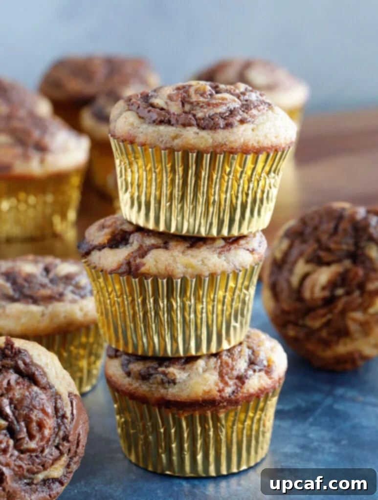 Delicious Nutella Banana Swirl Muffins A stack of perfectly baked Nutella Swirl Banana Muffins, showcasing the enticing chocolate hazelnut swirls on top.