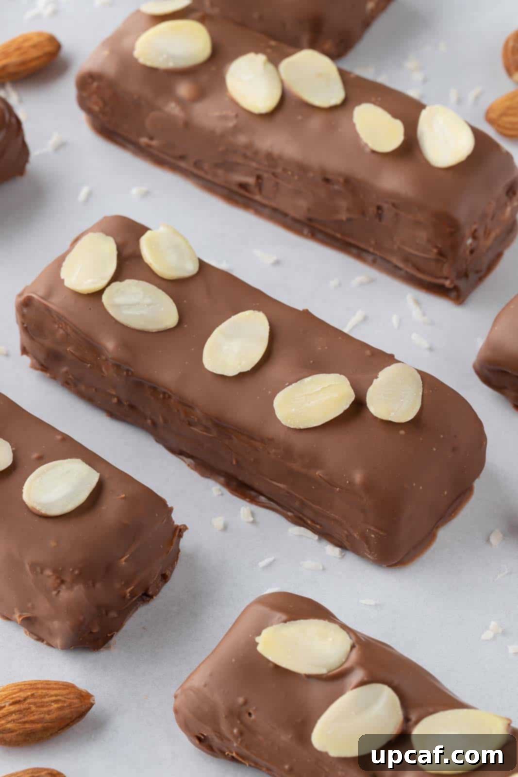 Island Coconut Chocolate Dream 10 Candy bars topped with slivered almonds are neatly arranged on a tray, ready to be enjoyed or stored.