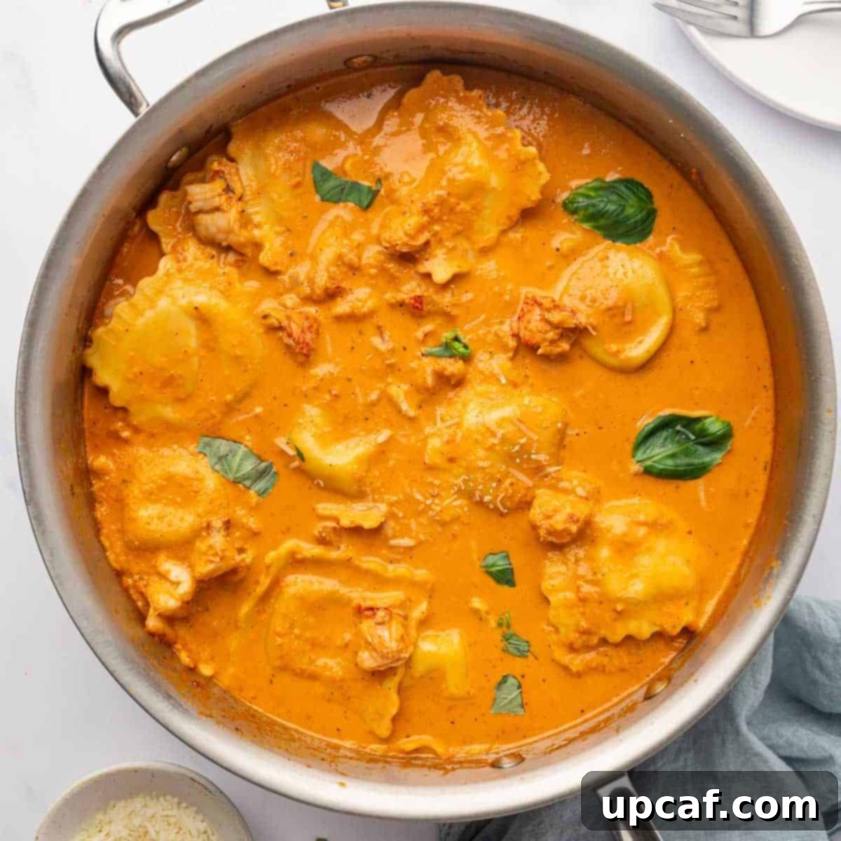 Decadent Lobster Ravioli Sauce 9 Ravioli is added to the cream sauce in a skillet.