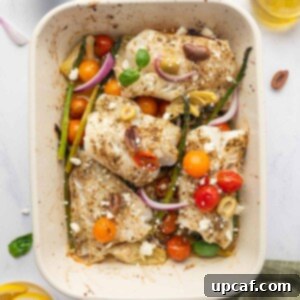Seasoned cod fish in a rectangle baking dish with asparagus, tomatoes and onions.