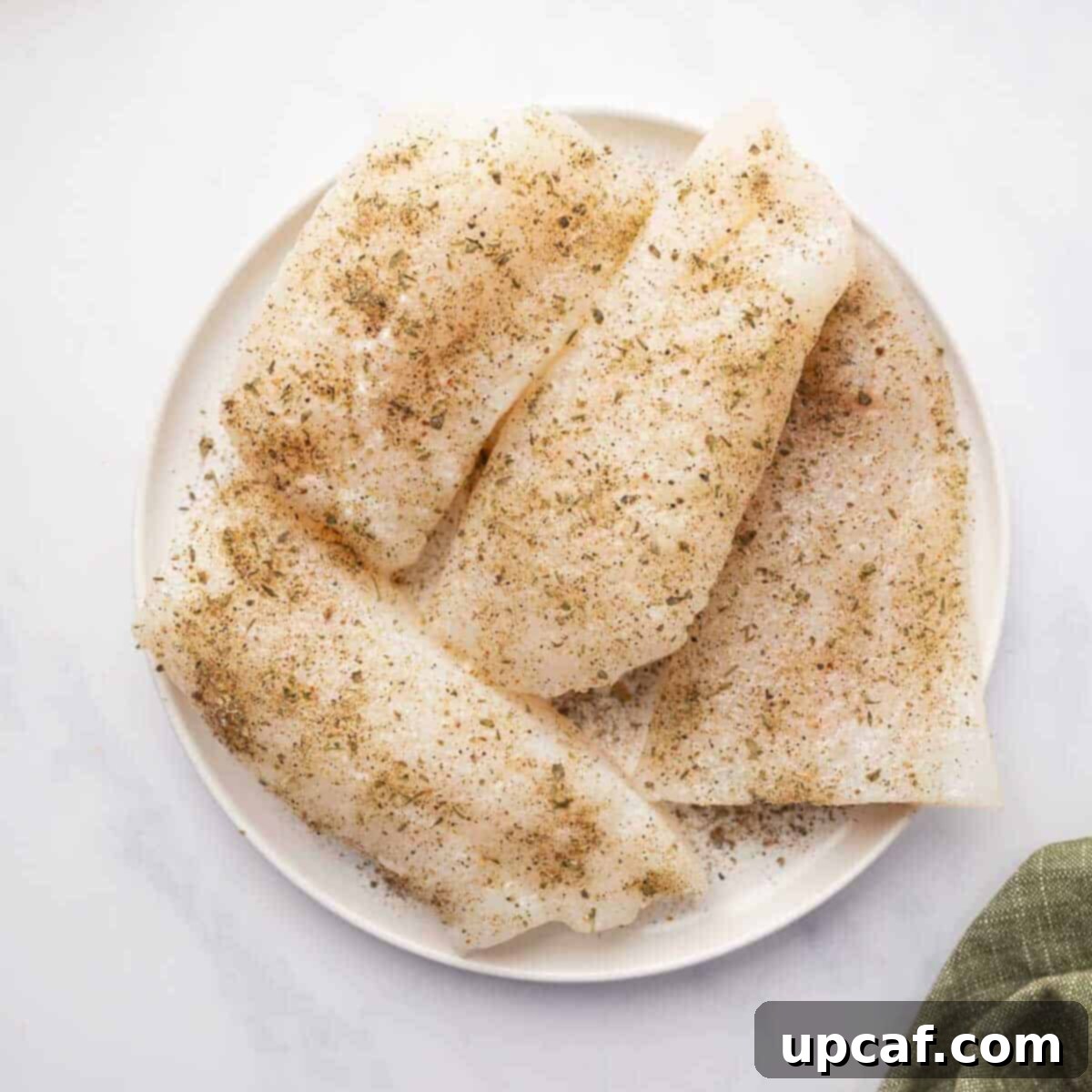 Seasoned cod filets are on a plate.