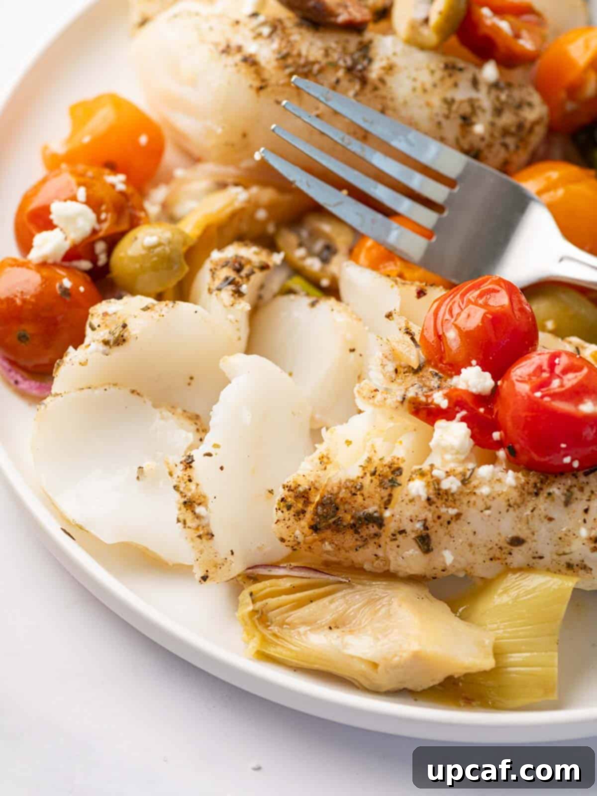 A fork flakes a piece of mediterranean cod.
