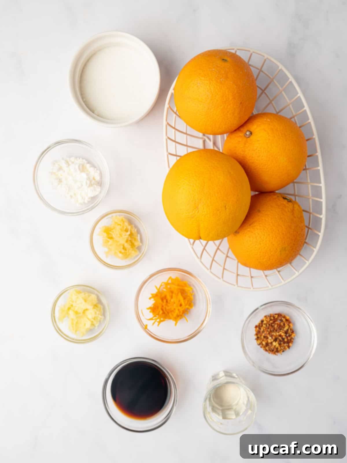 Ingredients laid out for making homemade orange chicken sauce, including fresh oranges, ginger, garlic, and sauces.