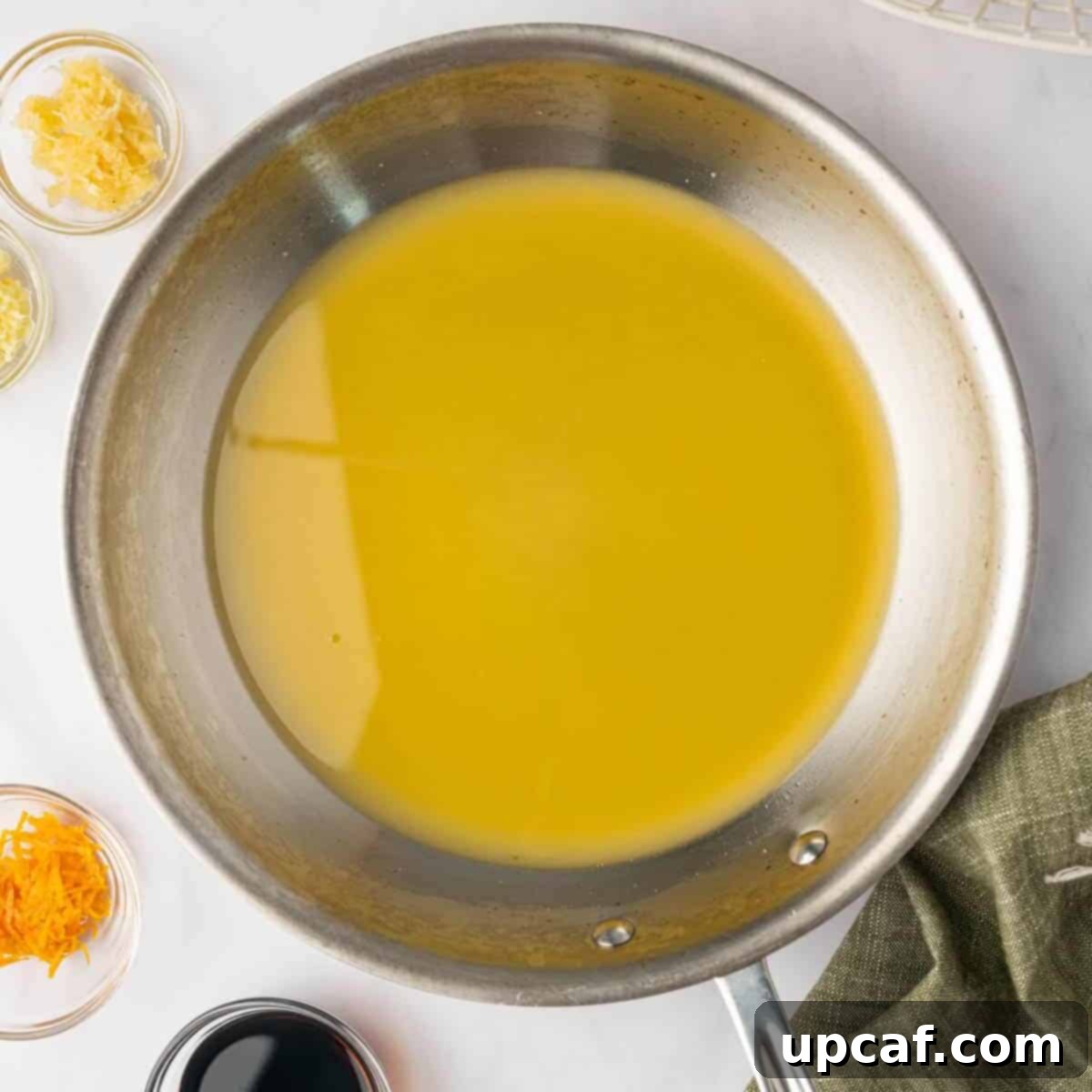 Fresh oranges being juiced into a saucepan for the orange chicken sauce.