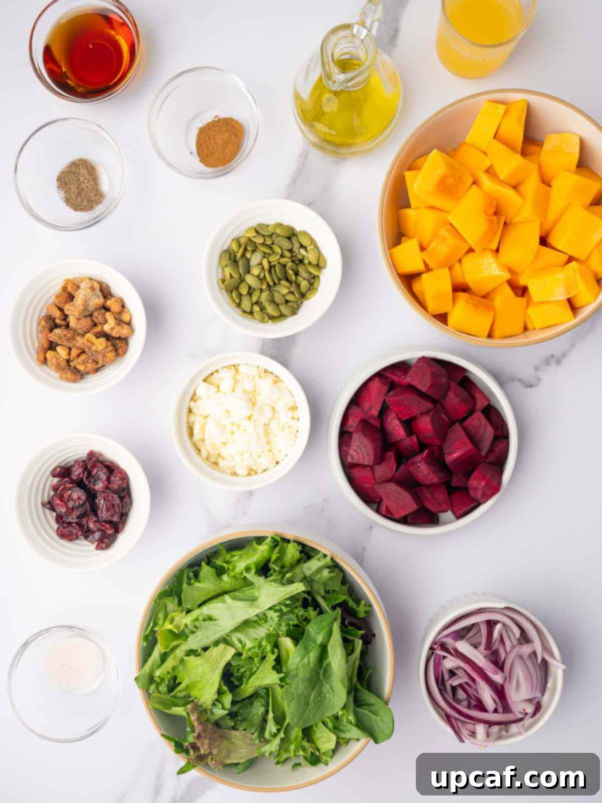 Roasted Butternut Feta Salad 3 A vibrant flat lay showcasing all the fresh ingredients needed for a butternut squash feta salad, including cubed squash and beetroot, mixed greens, crumbled feta, pumpkin seeds, and oranges for the dressing.