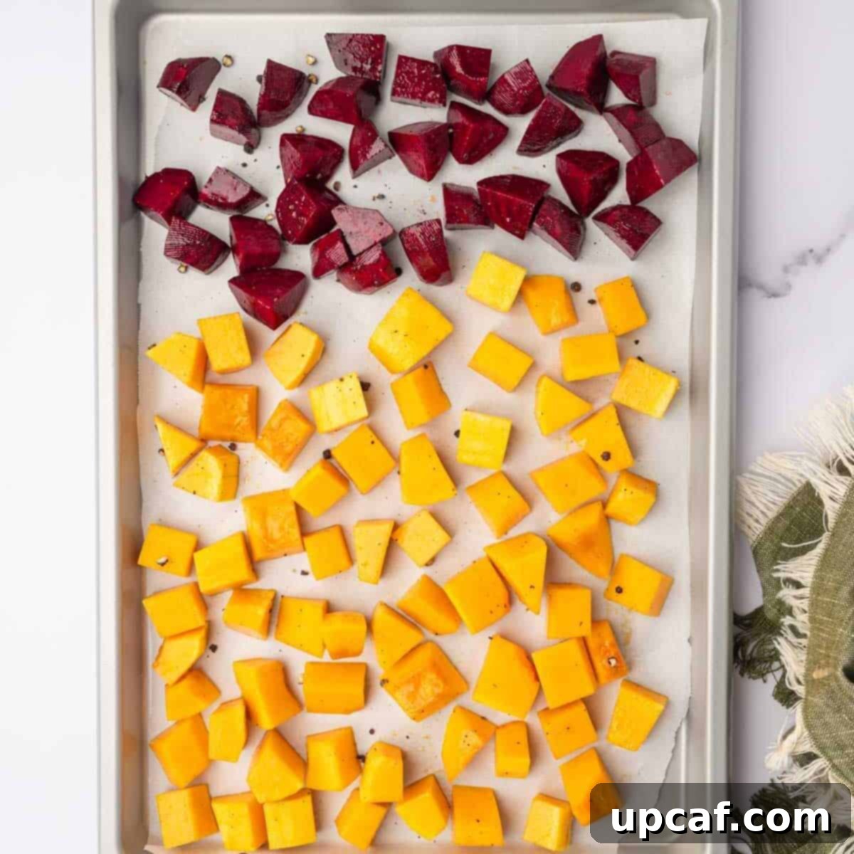 Roasted Butternut Feta Salad 5 Cubed beets and butternut squash are spread evenly on a parchment-lined baking tray, ready for roasting until tender and golden.