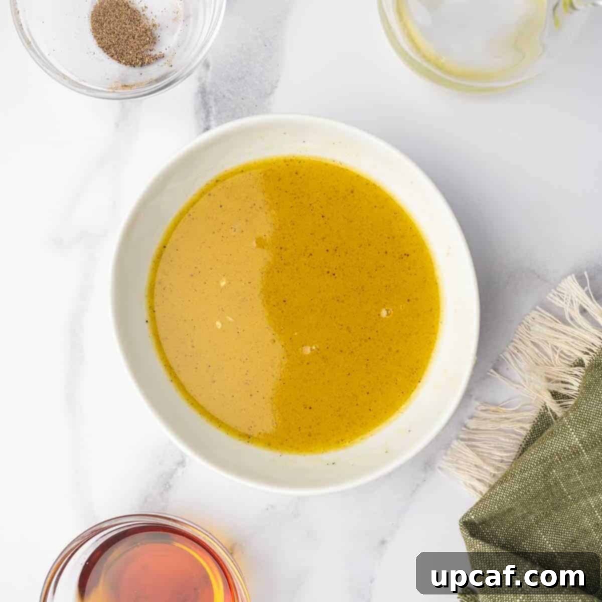 Roasted Butternut Feta Salad 7 A small bowl containing a golden maple citrus dressing, with a whisk resting in it, ready to be drizzled over the salad.