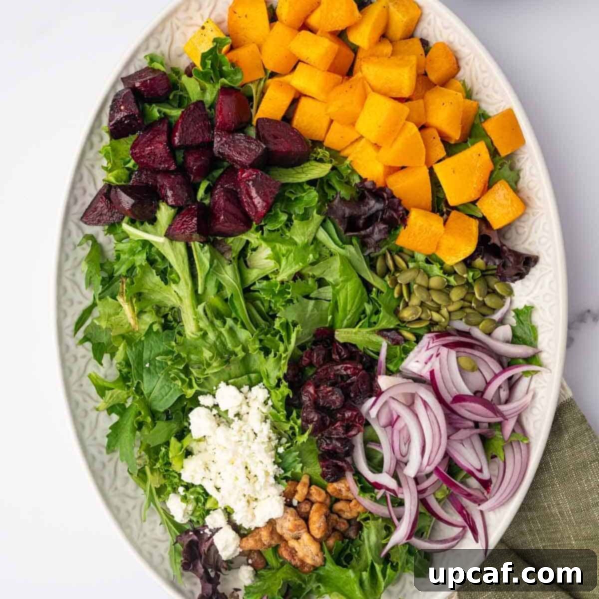 Roasted Butternut Feta Salad 8 The assembled Butternut Squash and Feta Salad on a large platter, with roasted vegetables added to the mixed greens and toppings, just before being drizzled with dressing.