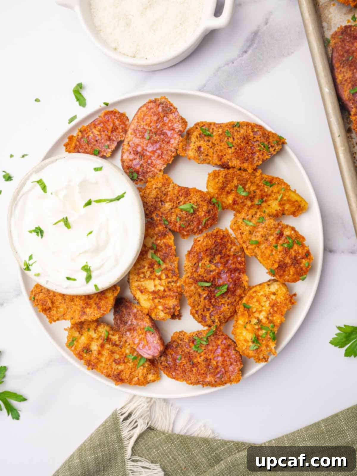 A plate of cheesy potatoes with a small bowl of dip.