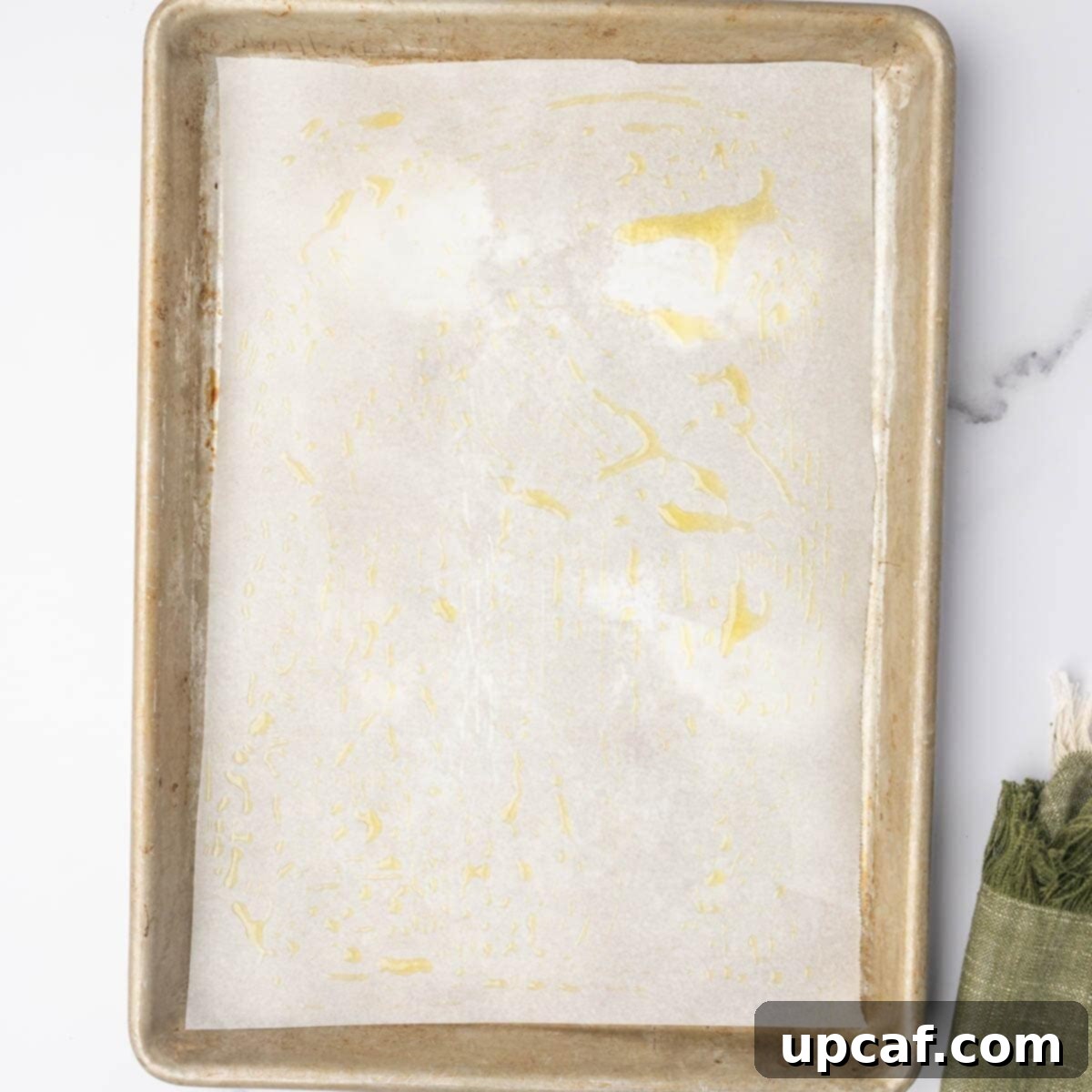 Olive oil is sprinkled on a baking sheet.