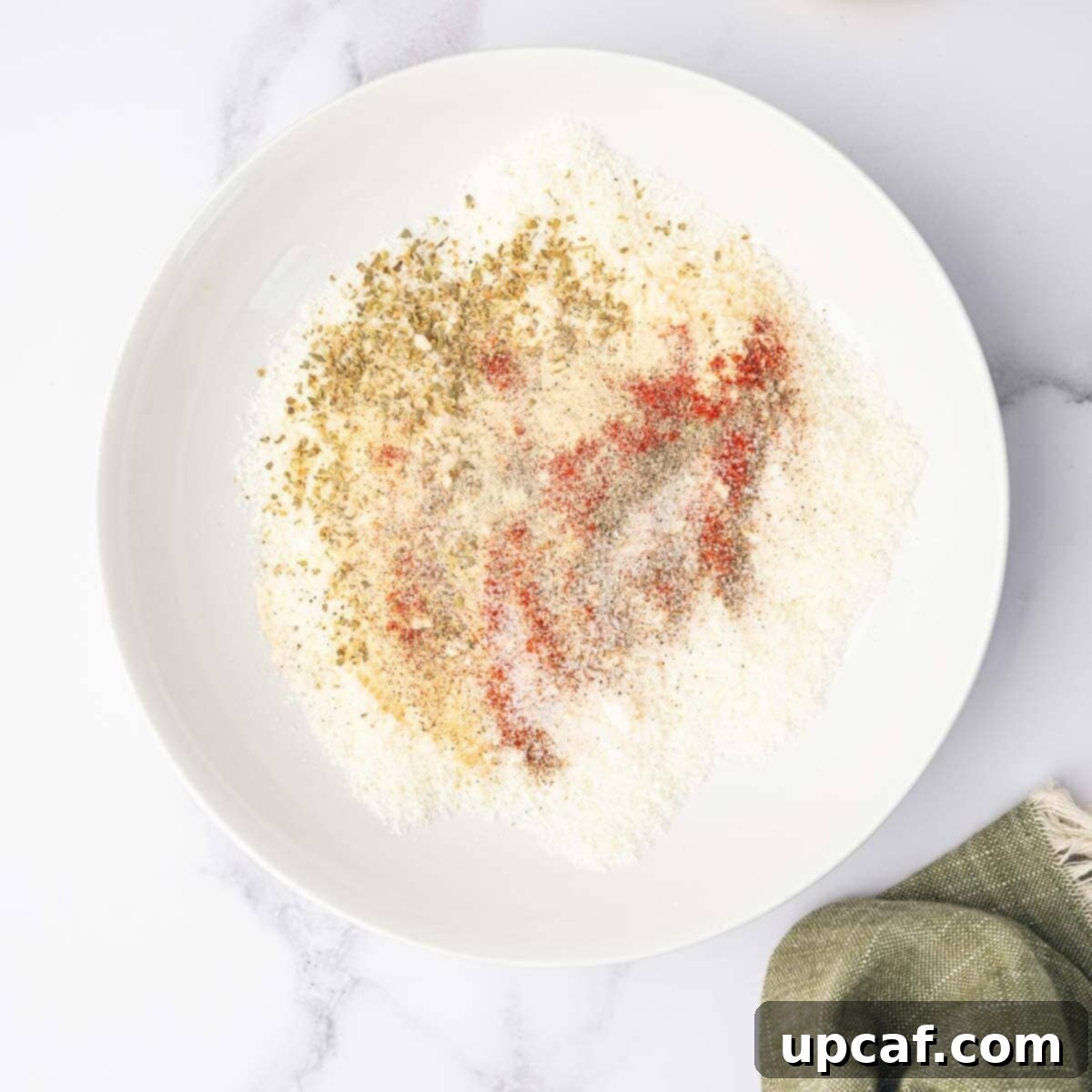 Cheese and seasonings are combined in a bowl.