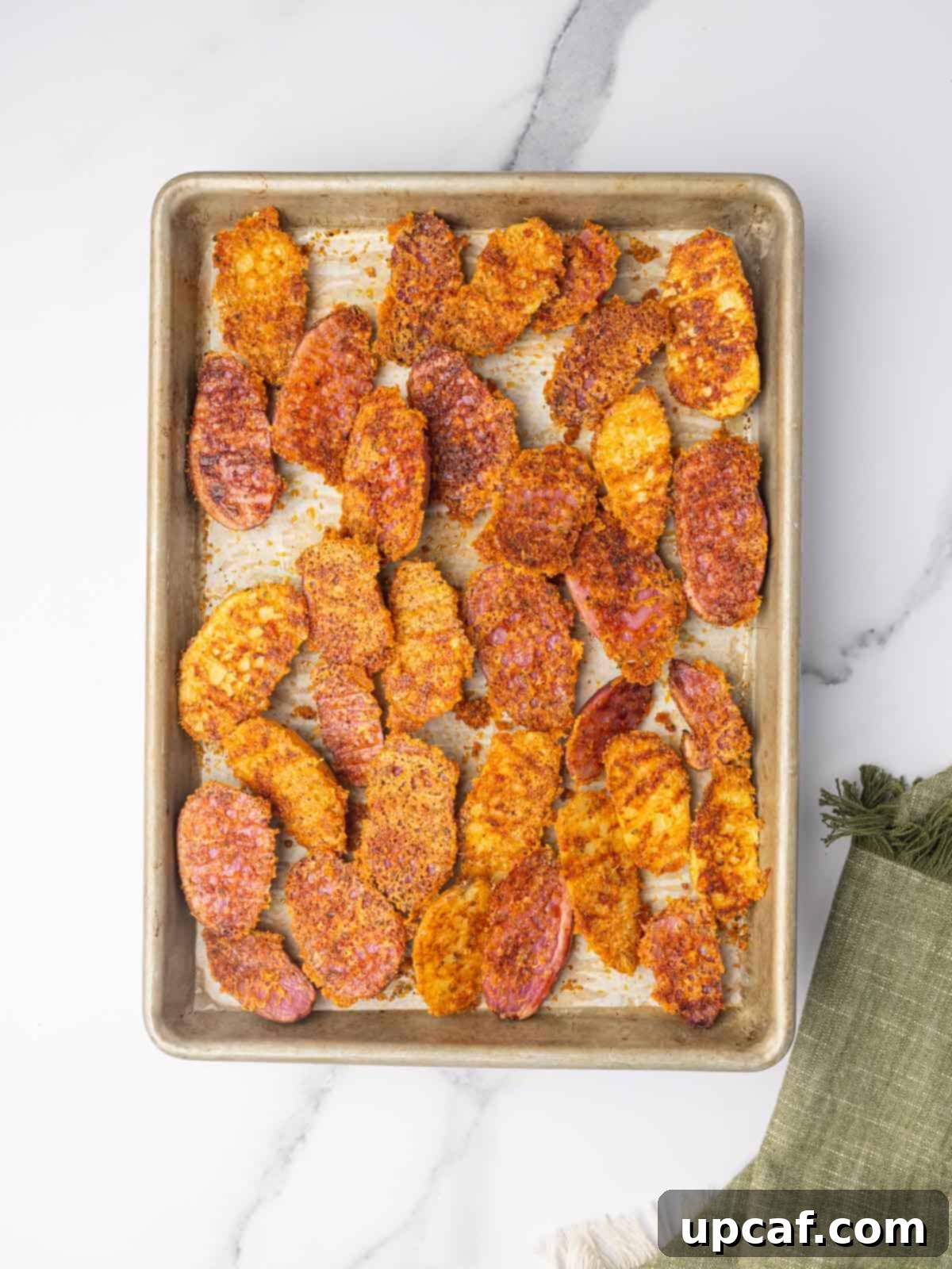 Potatoes with a crispy cheese layer on a tray.