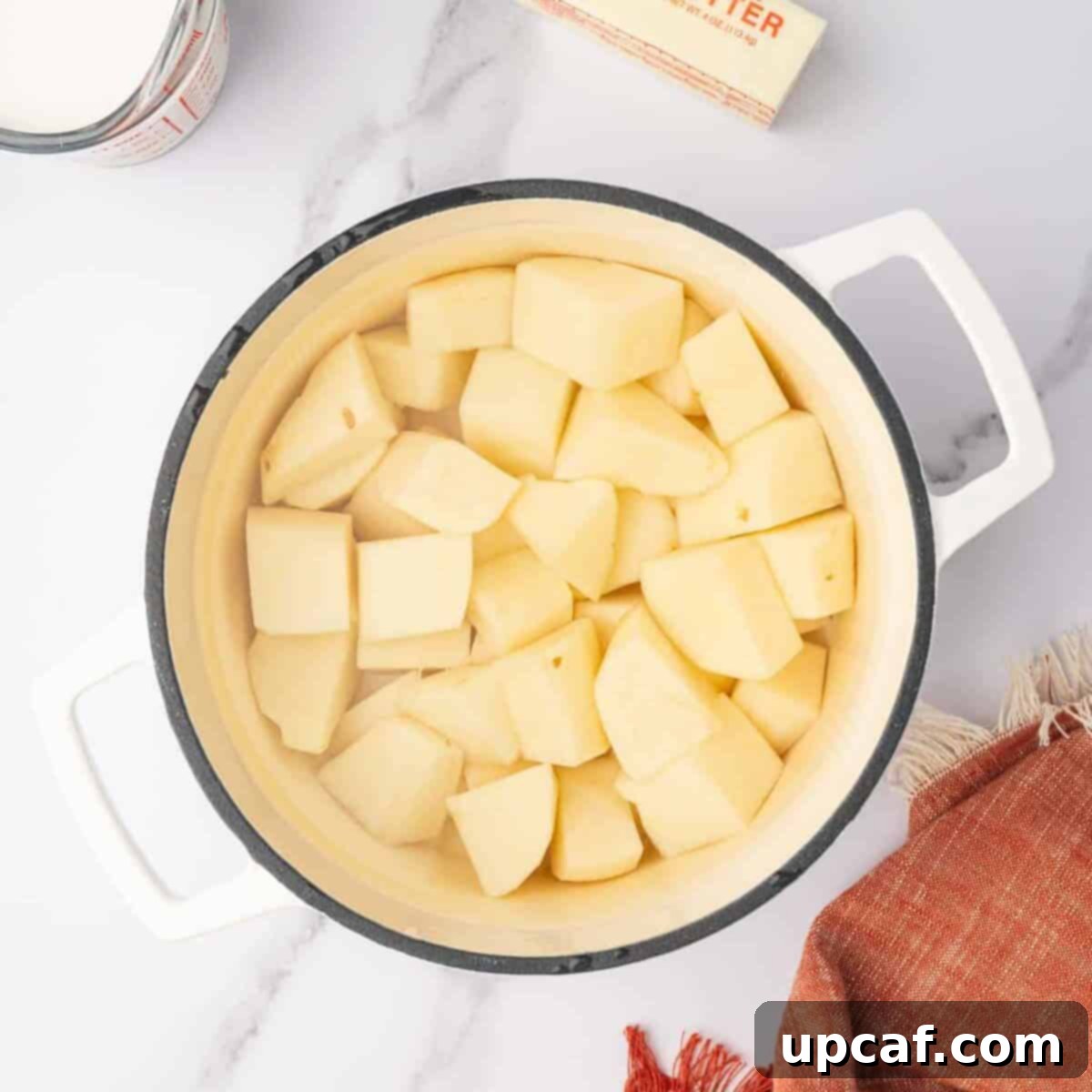 Decadent Cheesy Mash 4 Cubed potatoes are in a stock pot, ready for boiling.