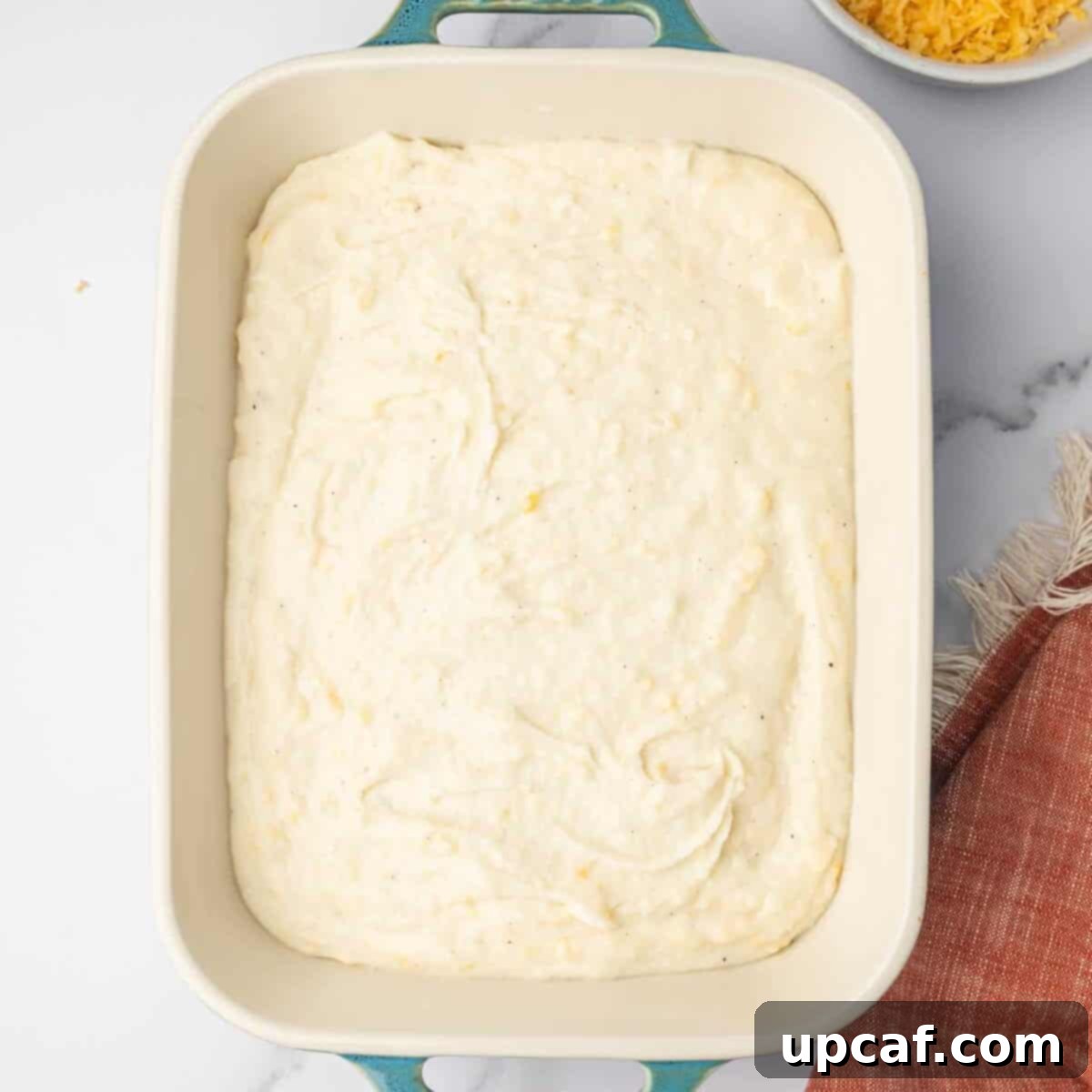 Decadent Cheesy Mash 8 Mashed potatoes are spread evenly into a prepared baking dish.