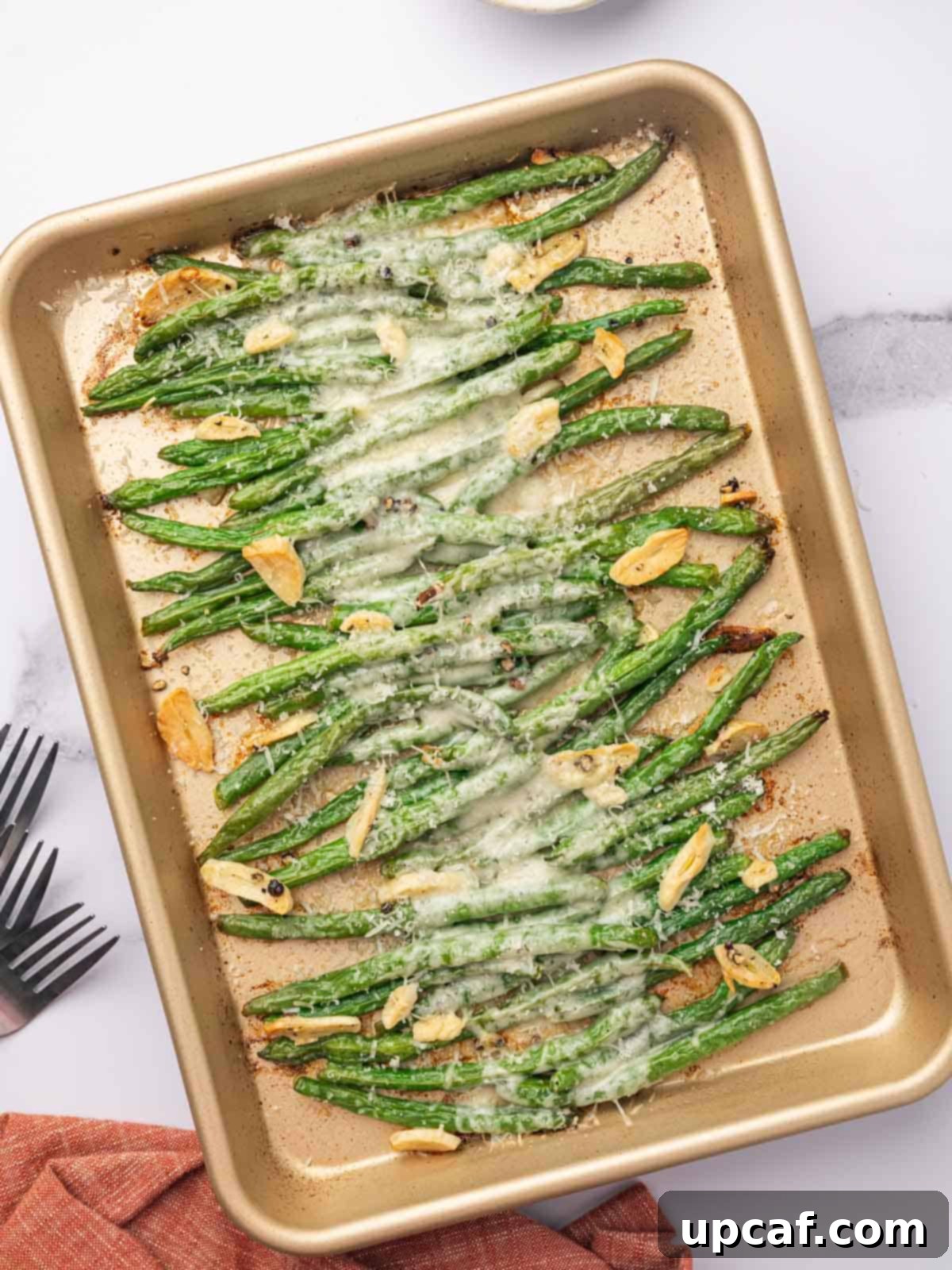 Garlic Parmesan Green Beans topped with melted cheese on a metal baking tray, ready to be served.