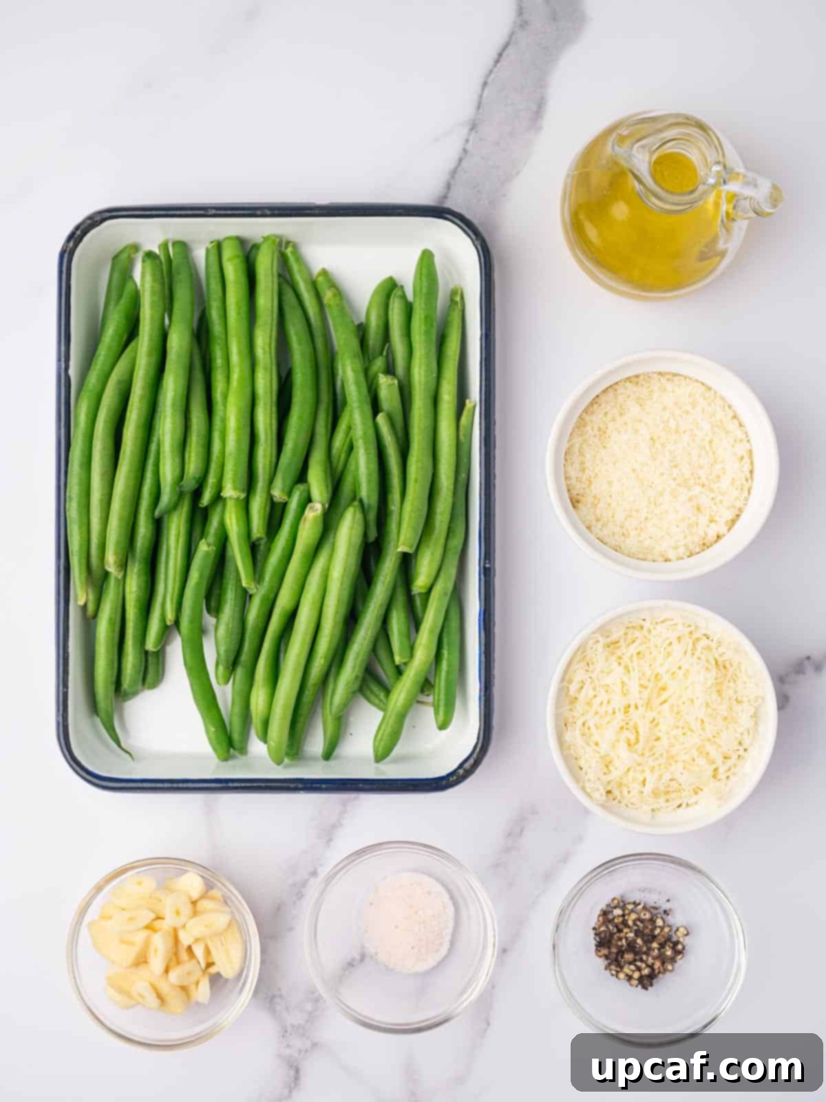 All ingredients laid out on a wooden board, including fresh green beans, garlic, olive oil, salt, pepper, and two types of cheese.
