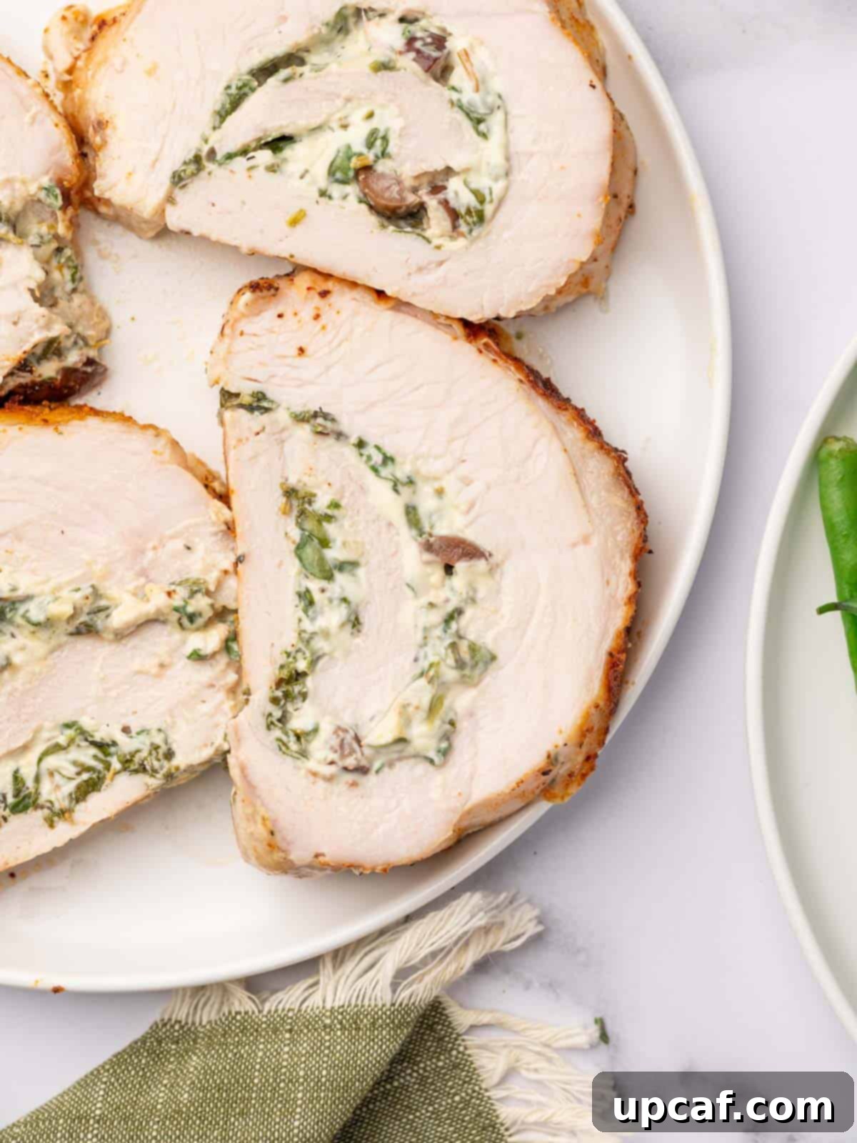 Savory Stuffed Turkey Roll 11 Delicate slices of stuffed turkey breast are artfully arranged on a pristine white plate, showcasing the vibrant filling within.