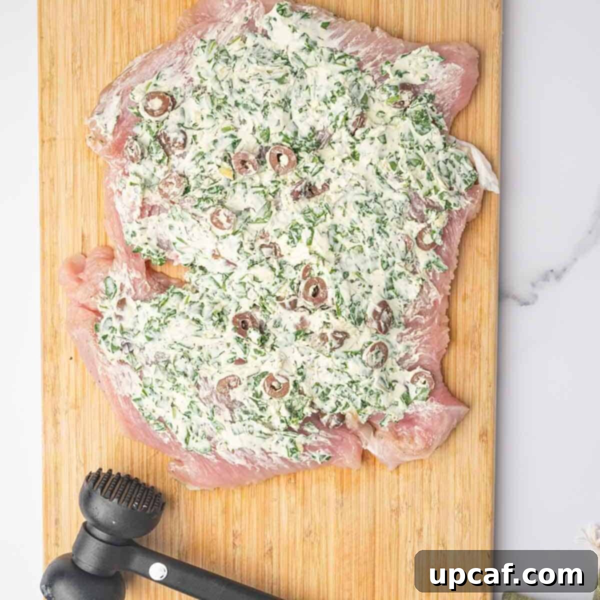 Savory Stuffed Turkey Roll 6 The creamy stuffing mixture is generously and evenly spread across a flattened, boneless turkey breast laid out on a cutting board.