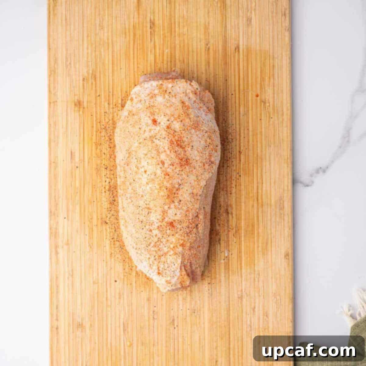 Savory Stuffed Turkey Roll 7 A raw, seasoned stuffed turkey roll, ready for roasting, rests on a clean cutting board.