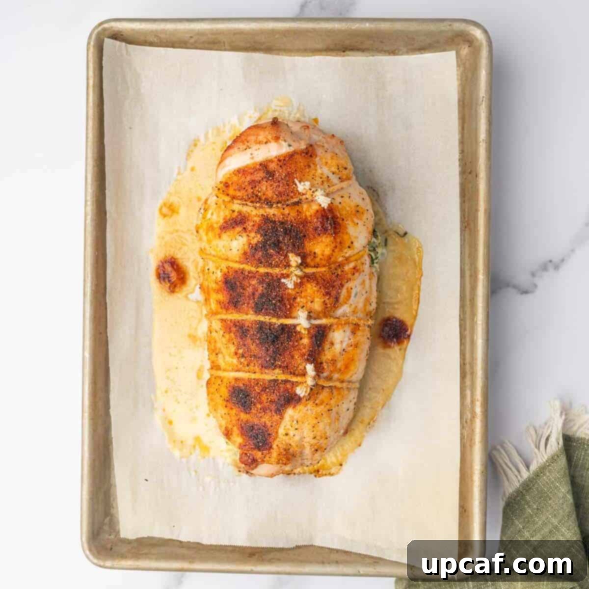 Savory Stuffed Turkey Roll 9 A perfectly cooked, golden-brown stuffed turkey breast rests on a baking sheet, having just come out of the oven.