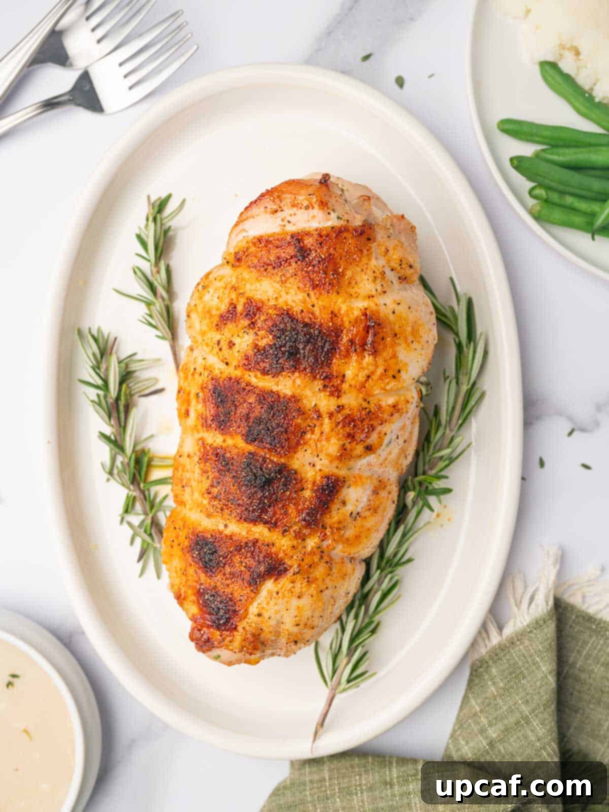 Savory Stuffed Turkey Roll 10 A beautifully golden, cooked stuffed turkey breast sits proudly on a serving platter, garnished with fresh rosemary sprigs, ready to be enjoyed.