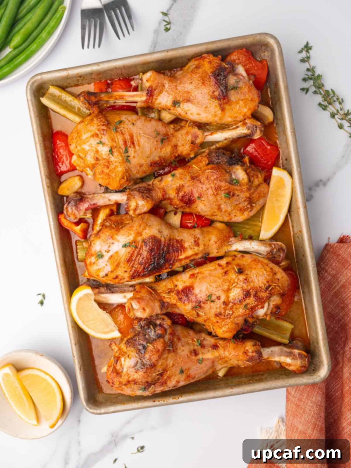 Golden brown and juicy drumstick on a sheetpan with roasted vegetables.